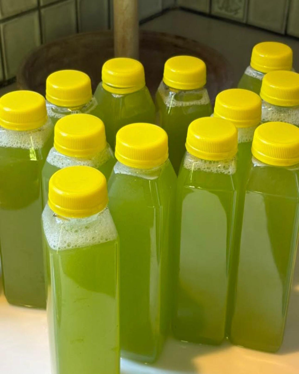 Kae Health Juice bottles filled with green liquid for 7 day green juice cleanse with yellow caps
