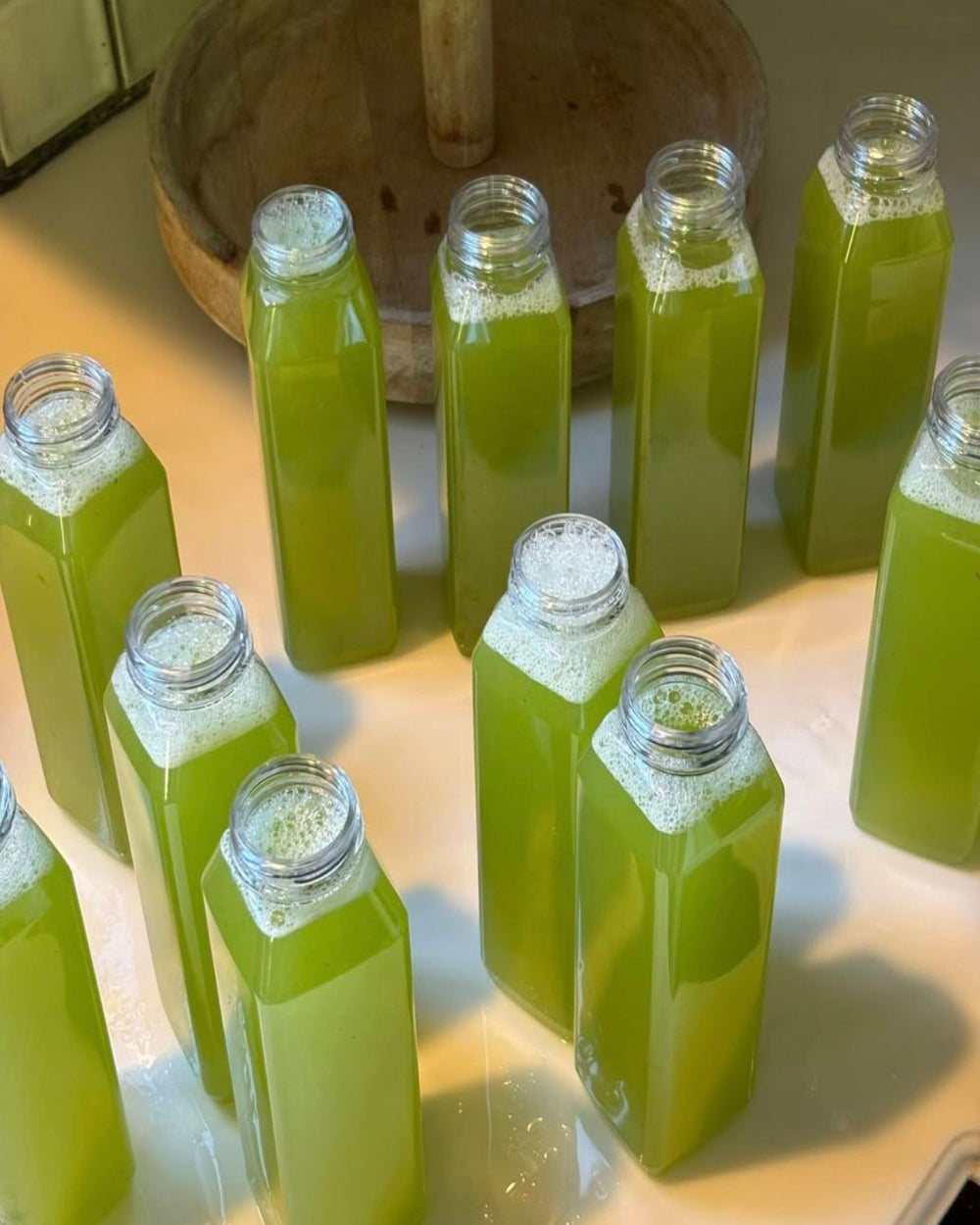Bottles of cold pressed honey dew juice with green color arranged on a white surface