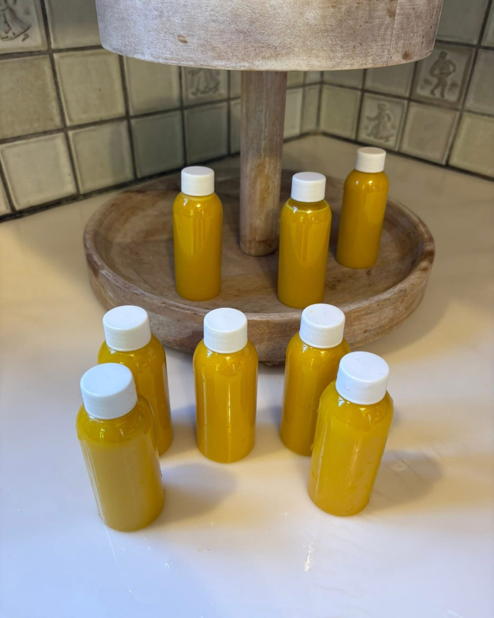Kae Health Juice small yellow bottles arranged on wooden stand ginger shot Detroit delivery